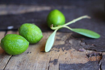 Wall Mural - Green olive leaves and olives on shabby wooden table background. Flat lay, top view. Mediterranean design.