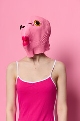 Wall Mural - Woman in a fish costume for Halloween poses against a pink background in a crazy scary costume with a pink silicone mask on her head