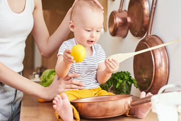 A adorable baby boy with a young mother playing in the kitchen.