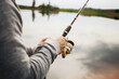 Fishing rod isolated on lake background. Man catching fish with a rod. Fishing equipment background. Small fishing pond. Leisure and recreation in the nature.
