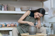 © whyframeshot - Close up of female hands working on potters wheel,asian female sculpture woman shaping mold small vase bowl clay on potter's wheel at home studio workshop art and creation hobby concept