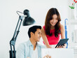 © tete_escape - Close-up Asian business couple, young man and woman, colleagues using tablet and laptop computer on table, looking at screen, working together at the white clean small office background.