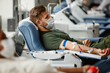 canvas print picture Side view portrait of military soldier donating blood while lying in chair at donation center and wearing mask, copy space