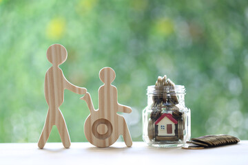 Employee volunteer assistant with man on wheelchair and model house in the glass bottle on natural green background,Save money for prepare in future and handicapped person concept