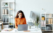 © Seventyfour - Young adult Caucasian female CEO siting at desk in modern office working with documents using laptop