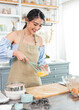© NaMong Productions - young Asian housewife in kitchen cooking the bakery dough homemade.
