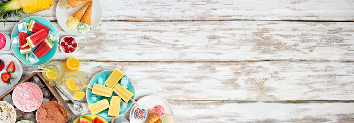 Refreshing summer foods corner border. Selection of ice cream, popsicles and fruit. Top down view over a white wood banner background.