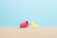 Yellow Rubber Ducky And Pink Bucket On The Beach Sand. Minimal Summer Vacation Composition.