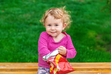 Poster - The child eats chips in the park. Selective focus.