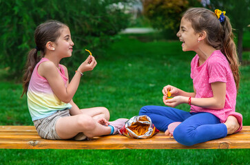 Children eat chips in a friend's park. Selective focus.