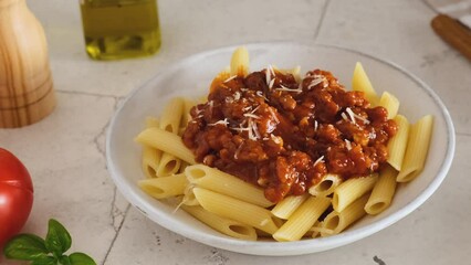 Wall Mural - A man hand sprinkle parmesan cheese in pasta penne with bolognese sauce. Italian cuisine. Tasty food for lunch or dinner. 4k video