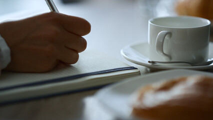 Woman hand writing notepad sitting cafe working paperwork notes in restaurant.