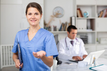 Female Doctor Making Welcome Gesture, Politely Inviting Patient In Medical Office