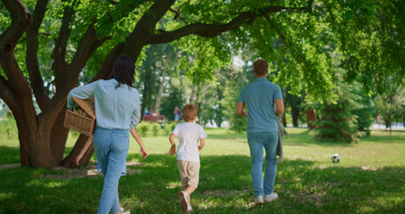 Wall Mural - Walking family find place for picnic back view. Active leisure on nature concept