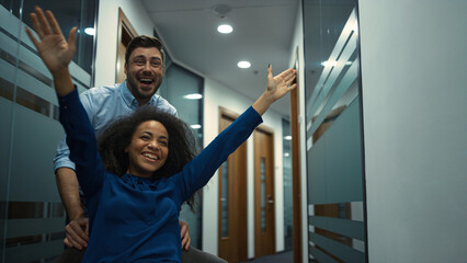 Wall Mural - Multiethnic business team celebrating success in company. Office chair race.