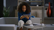 Smiling african american professional woman scrolling phone tablet in office.