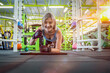 © somchairakin - Low angle of strong beautiful fitness girl standing in plenk position on elbows in athletic workout. Young woman bodybuilder doing plank exercise in studio.