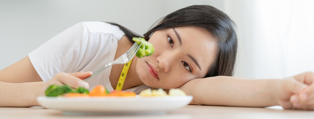 Diet in bored face, unhappy beautiful asian young woman, girl on dieting, holding fork in salad plate, dislike or tired with eat fresh vegetables. Nutrition of clean, healthy food good taste.