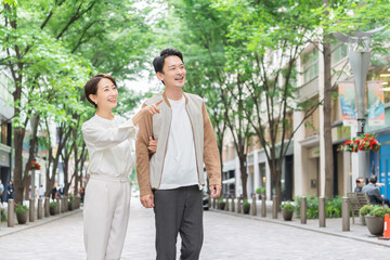 Canvas Print - 笑顔で新緑の街並みを歩く日本人夫婦・カップル