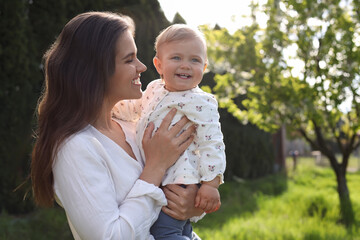 Wall Mural - Happy mother with her cute baby in park on sunny day, space for text