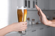 Man refusing to drink beer in kitchen, closeup. Alcohol addiction treatment