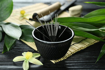 Composition with acupuncture needles on black wooden table