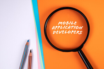 Wall Mural - mobile application developers. magnifying glass on an orange background