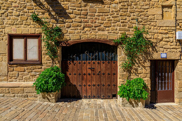 Wall Mural - Old stone house facade with a wooden gate on the streets in a picturesque medieval village of Ujue in the Basque Country, Navarra, Spain