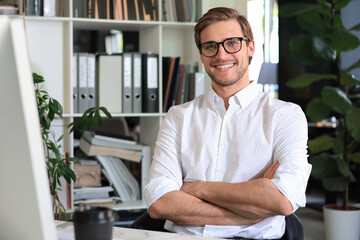 Sticker - Portrait of young man sitting at his desk in the office.