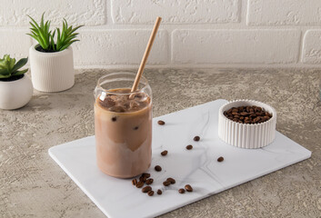 coffee latte, mocha with milk in a modern glass in the form of a can on a white marble board and a table made of concrete. a trend drink.