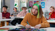 Teenage schoolgirl with green hair writing test in class in school