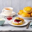 Scones with jam, clotted cream and cup of tea on marble table. Grey background. Close up.