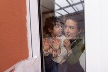 Mother And Daughter Looking Through Window