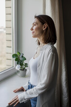 Happy Woman Standing In Front Of Window At Home