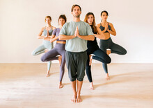 Man And Women Practicing Yoga In Front Of Wall At Fitness Studio