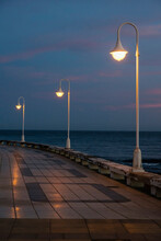 Illuminated Street Lights On Promenade By Sea