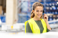 Happy Worker Talking Through Headset Working In Warehouse