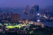 Egypt, Cairo, River Nile,Illuminated City Park At Dusk With River Nile And Skyscrapers In Background