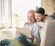 © Westend61 - Happy senior man with granddaughter using tablet PC at home