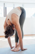 © Alla - Full length view of the elderly woman practicing yoga, standing in head to knees pose, working out at home. Stock photo
