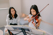 自宅でバイオリンの練習をする母と娘
