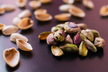 Wall Mural - close up of nutshells and salty green pistachios on black