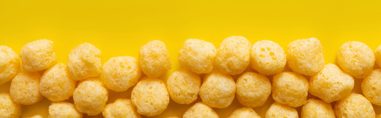 Canvas Print - top view of puffed and tasty cheese pops on yellow, banner