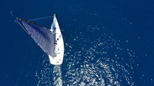 Aerial Drone Birds Eye View Photo Of Beautiful Sailboat With Blue Sails Cruising In The Deep Blue Aegean Sea, Greece