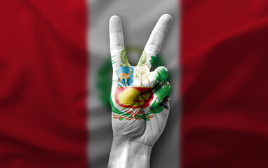 Hand making the V victory sign with flag of peru