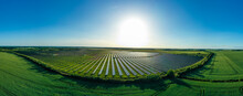 Panorama. Large Solar Power Plant On A Picturesque Green Field. Solar Panels In Aerial View. Power Plant Using Renewable Solar Energy With Sun.  Alternative Source Of Electricity.