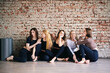 © khmelev - Cheerful women in activewear sitting near brick wall, yoga mats, ready start fitness training and rejoice at meeting. The concept of sports lifestyle and like-minded people. Yoga concept