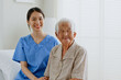 © Nattakorn - Portrait of young Asian woman, nurse, caregiver, carer of nursing home and senior Asian woman smiling at home. Look at camera