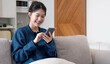© wichayada - Portrait beautiful young asian woman use smart mobile phone on sofa in living room interior
