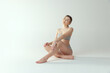© master1305 - Portrait of beautiful young woman sitting on floor in underwear, posing isolated over grey studio background. Tenderness